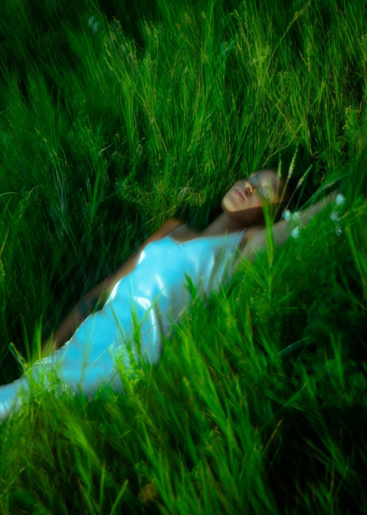 A woman of colour laying in grass at twilight