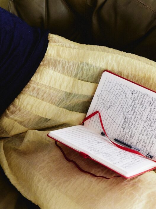 A person in a sweater and a skirt with a notebook in their lap