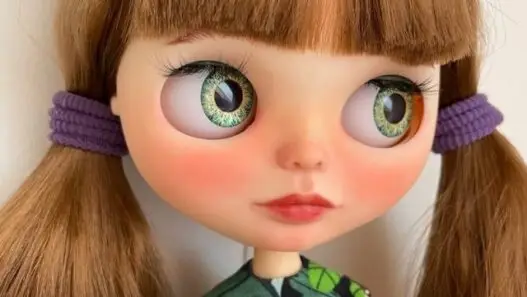 A custom OOAK Blythe doll with brunette hair in pig tails.