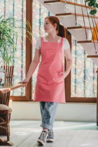 A redheaded woman wearing a pink utility apron